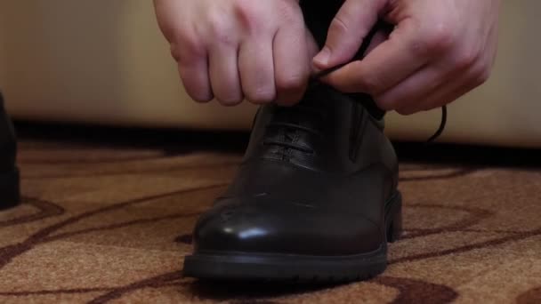 Man verbindt zijn schoenveters op zijn zwarte schoenen — Stockvideo