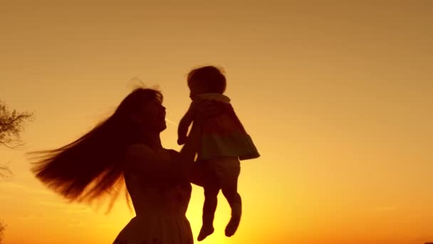 Мама танцює з маленькою дитиною на заході сонця. Щасливі сімейні прогулянки в парку влітку . — стокове відео