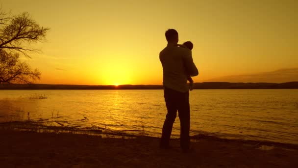 美しい湖を夕暮れ時彼は小さな娘を持つお父さん踊り. — ストック動画