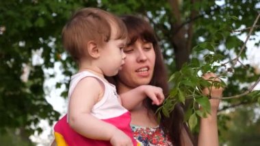 Anne ve çocuk yeşil yaprakları ağaçların sıcak yeşil park içinde arıyoruz.