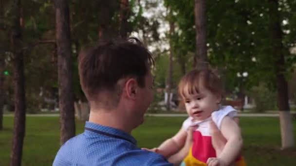 Тато кружляє дитиною на руках і сміється ходити з ним у місті . — стокове відео