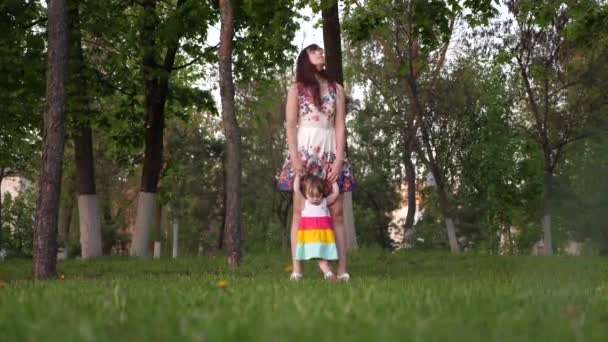 Meisje neemt haar eerste stappen lopen met haar moeder in park op een warme zomerdag — Stockvideo