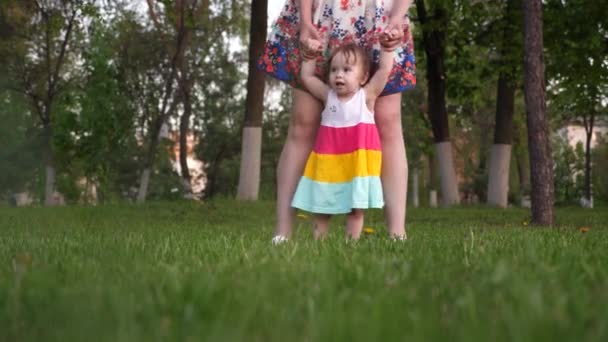 Mom learns to walk the child in the park on the green grass. — Stock Video