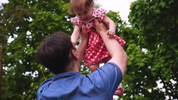 La niña está saltando en el aire en manos de papá y riendo. Movimiento lento — Vídeos de Stock
