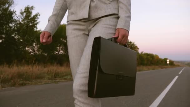 Womanbusinessman carries in his hand a black briefcase, a woman in trousers and a jacket walks along the asphalt, close up — Stock Video