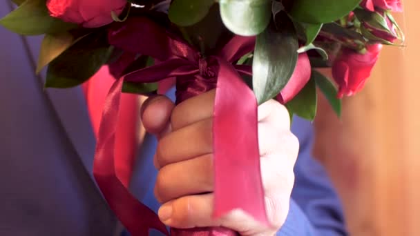 Человек в куртке и красном держит в руке красивый букет красных роз. close up — стоковое видео
