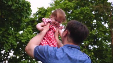 Baba çalış küçük kızı, Bebek elleriyle, yukarı atar ile çocuk mutlu ve gülüyor. Baba küçük kızı yaz parkta tutuyor.