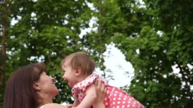 Anne çalış küçük kızı, Bebek elleriyle, yukarı atar ile çocuk mutlu ve gülüyor. küçük kız anne yaz parkta elinde çalış.
