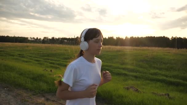 Sports lifestyle, girl in music headphones running on the road training — Stock Video