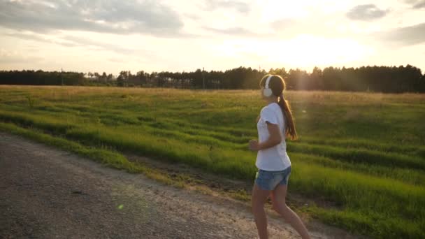 Flicka i musik hörlurar kör på väg utbildning, sport livsstil, Slow motion — Stockvideo