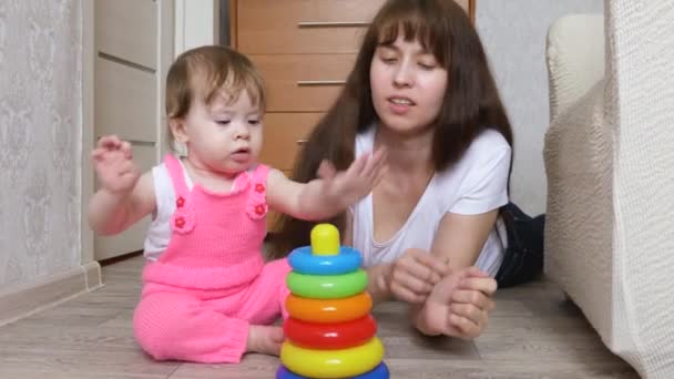 Mutter und kleine Tochter spielen in bunter Pyramide im Kinderzimmer. — Stockvideo