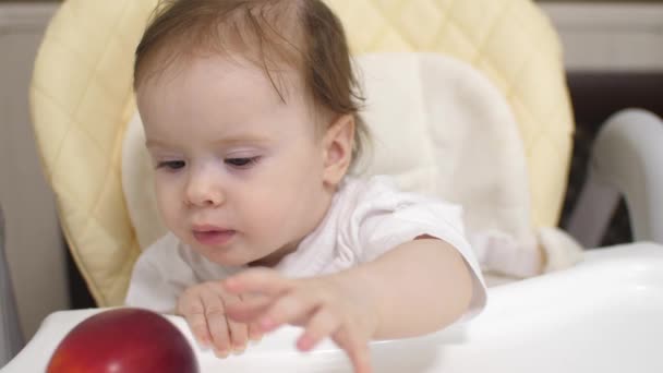 Petit enfant joue avec pomme rouge sur la table — Video