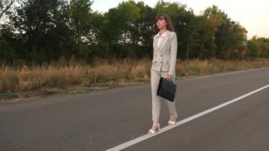 ince iş kadın onun elinde siyah evrak çantası ile asfalt üzerinde yürüyor. kız hafif bir takım elbise ve Beyaz Ayakkabı çalışmaya geliyor. Ağır çekim