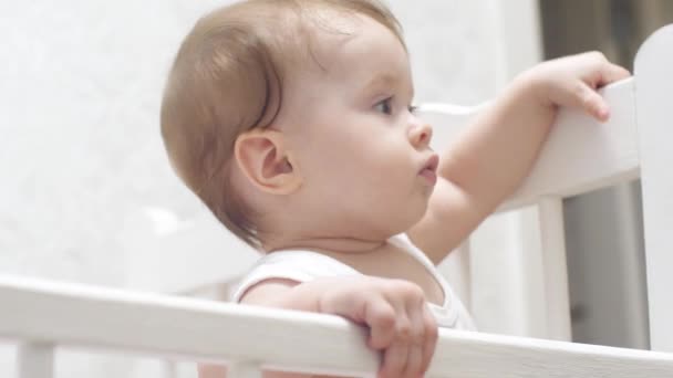 Baby stands on his feet, waves his hand and talks. — Stock Video