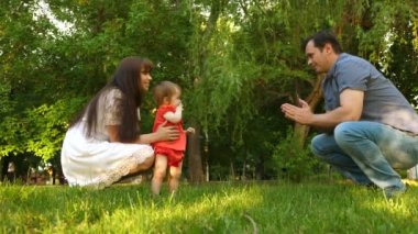 Bebek çim çimen üzerinde anne ve baba ile ilk adımlar alır.