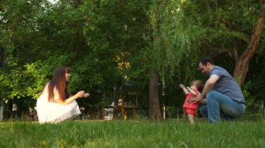 Bebek çim çimen üzerinde anne ve baba ile ilk adımlar alır.
