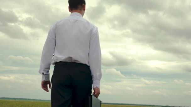 Businessman is walking with briefcase in his hand against background of dark clouds — Stock Video