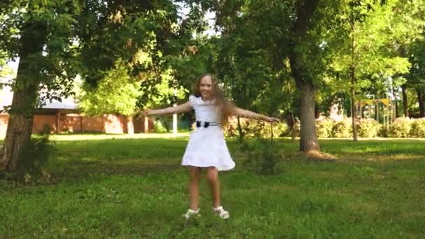 Fröhliches Mädchen tanzt und wirbelt im weißen Kleid in einem Sommerpark. — Stockvideo