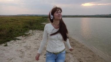 Kulaklık ile dans neşeli kız bir tablet ile akşam ve müzik sahile gidiyor.