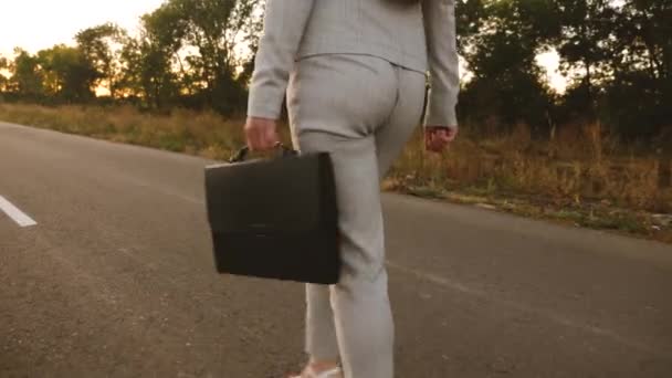 Businesswoman with black briefcase in her hand goes to work on road, view from the back, close up — Stock Video