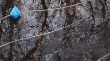Sonbahar parkta şeffaf Nehri'nin akış ile küçük mavi kağıt tekne yüzen