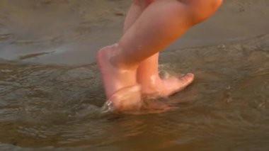küçük bir çocuğun bacakları su üzerinde gidin. Ağır çekim. yakın çekim.