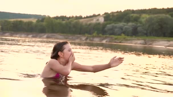 Девушка в купальнике ныряет под воду и смеется в летний вечер. Пляжный сезон. Медленное движение — стоковое видео