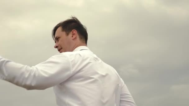 Businessman in white shirt and tie is playing with paper flying airplane against background of dark clouds. businessman resting from work outdoors in the countryside. — Stock Video