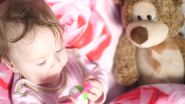 Pequeno bebê está no travesseiro e rói brinquedo . — Vídeo de Stock