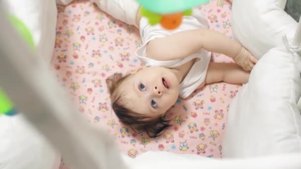 Child lies in cradle and looks at the rotating toys. — Stock Video