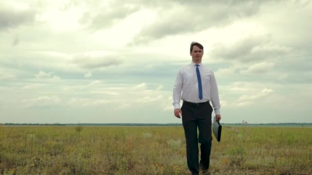 Agronom går över fältet. affärsman i vit skjorta och blå slips bär i sin hand svart portfölj med dokument. — Stockvideo