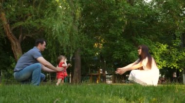 küçük bebek anne ve baba ile bir yaz parkta yürümeyi öğrenir