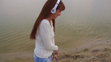 kulaklık kız sahilde bir tablet ile gider ve müzik, güzel kız gülüyor ve gülümsüyor için dinler