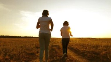 Genç kız kulaklık kırsal kesimde koşu spor yapıyor. Genç kızlar günbatımında eğitimi ve müzik