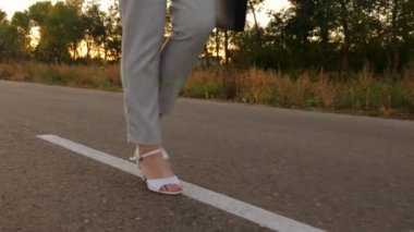 ince bacakları asfaltta yürüyerek. Kız Beyaz Ayakkabı işe giderken gider. Elinde siyah bir evrak çantası taşıyor. Ağır çekim