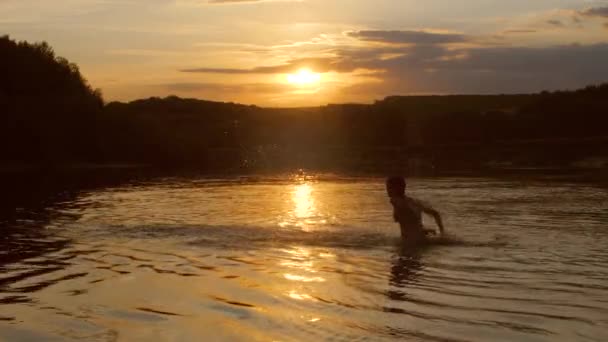 Tienermeisje spatten water bij zonsondergang. — Stockvideo