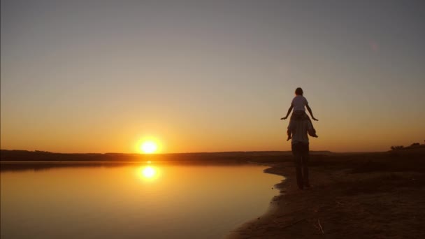 Tata dziecko krąży, który siedzi na ramionach, o zachodzie słońca. Zwolnionym tempie. — Wideo stockowe