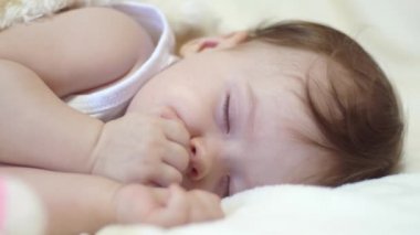 Onun için preslenmiş yumrukları ile bebek uyur.