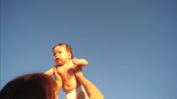 Baby opgegroeid in blauwe hemel door moeder handen, slow-motion — Stockvideo