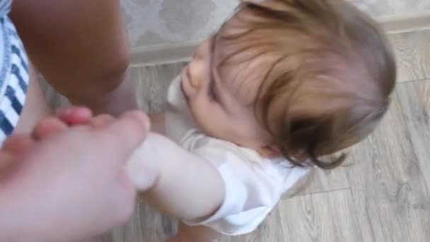 小さな赤ちゃんは、ジャンプと笑って、お母さんの手を握る. — ストック動画