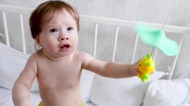 küçük çocuk karyolasında duran ve oyuncaklar ile oynama.