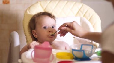 Küçük bebek kaşık mutfak sandalyede oturan püresi yiyor