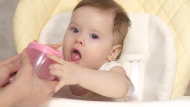 Мати дає пити воду дитини зі скла, дитина їсть за дитячим столом — стокове відео