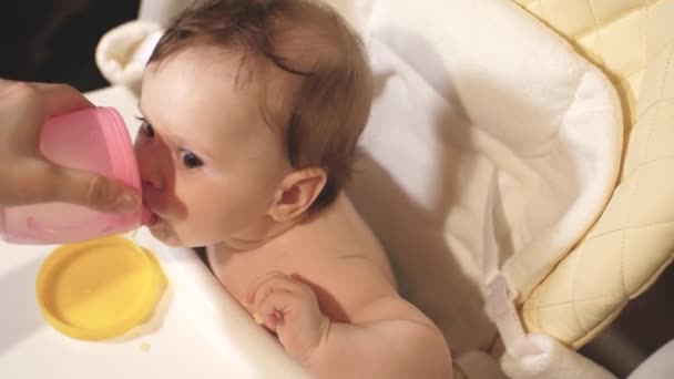 Moeder geeft om water te drinken van de baby na de voeding. kind dranken water aan tafel — Stockvideo