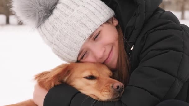 Chica abrazando a su perro favorito en invierno en el parque. Camina con tu mascota durante las vacaciones de Navidad . — Vídeo de stock