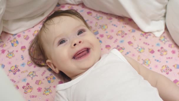 O bebê está sorrindo deitado na cama . — Vídeo de Stock