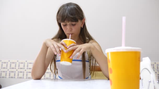 Ragazza si siede a tavola nel caffè, beve un delizioso cocktail e sorride . — Video Stock