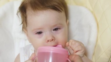 küçük çocuk bir çocuk koltuğuna oturur ve Childs'ın cam suyu içer.