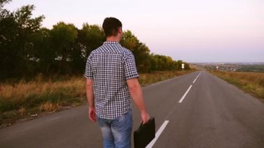 Elinde siyah bir çanta ile asfalt yol boyunca yürüyüş ekose gömlekli erkek iş adamı