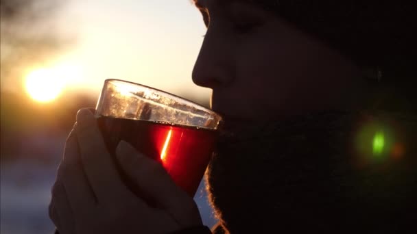 在夕阳明媚的阳光下 年轻美丽的女人正在喝着透明玻璃的茶 妇女在公园喝茶 — 图库视频影像